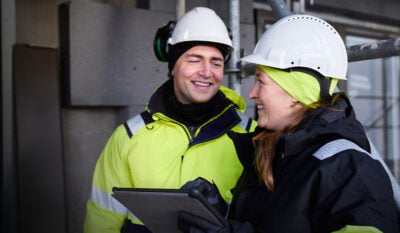 man och kvinna iklädda i varselkläder arbetar tillsammans på byggarbetsplats