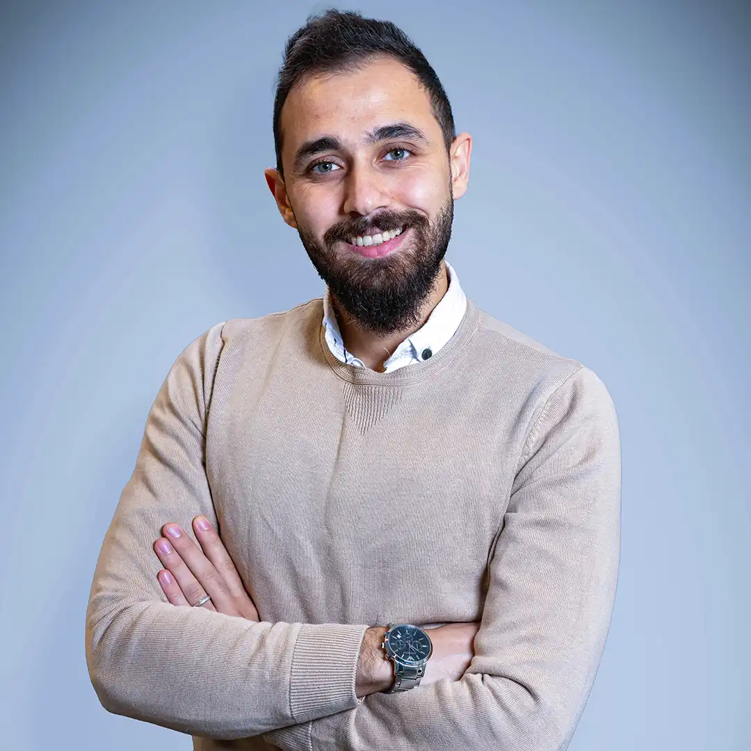 Porträttbild av Amjad som har läst kursen kyl- och värmepumpsteknik. Han står med armarna i kors och ler.